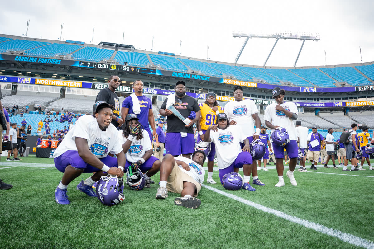 Football athletes pose together on the field at a stadium